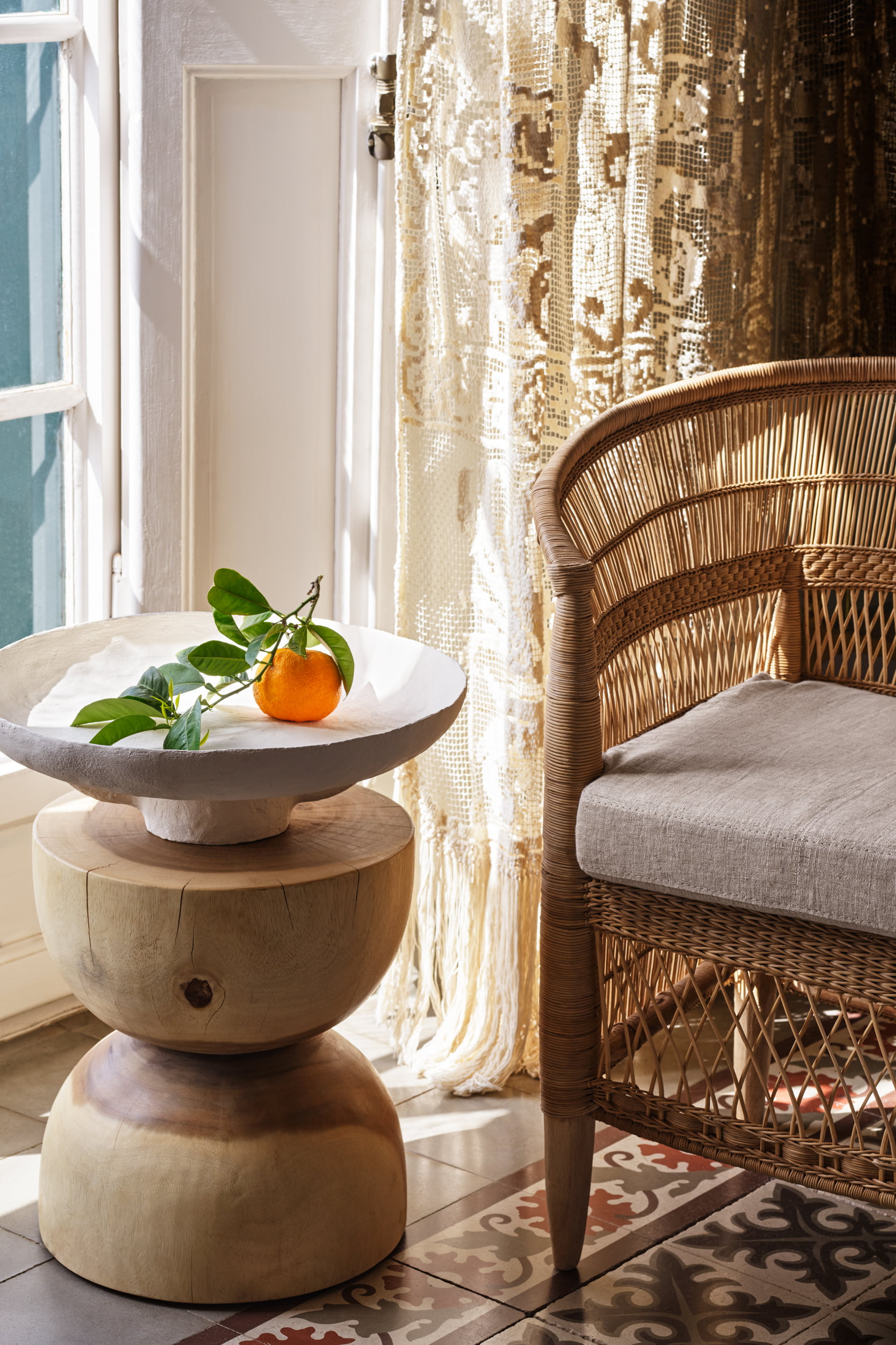 Mesa auxiliar con decoración de frutas junto a una silla de mimbre