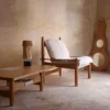Butaca de madera con cojines blancos en un ambiente rústico y acogedor de La Maison Barcelona, ideal para una decoración cálida