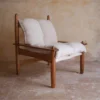 Butaca de madera con cojines blancos en un ambiente rústico de La Maison Barcelona, ideal para espacios acogedores
