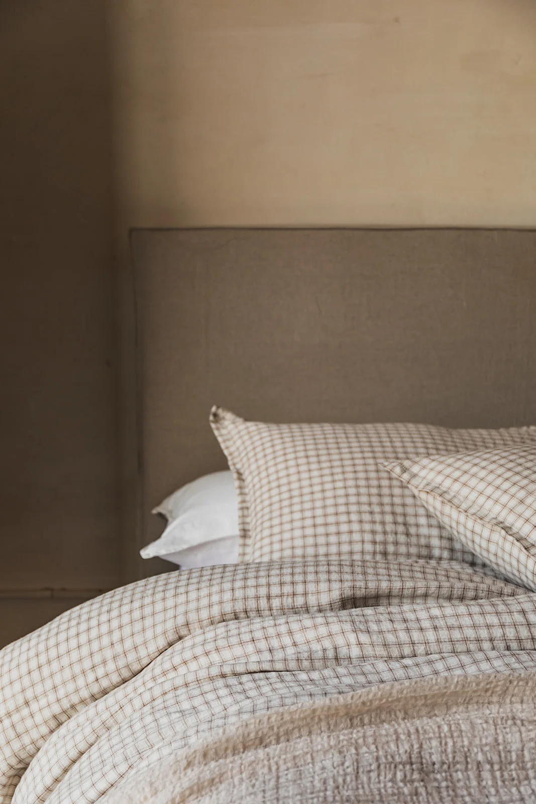 Detalle de manta de cuadros beige sobre cama.