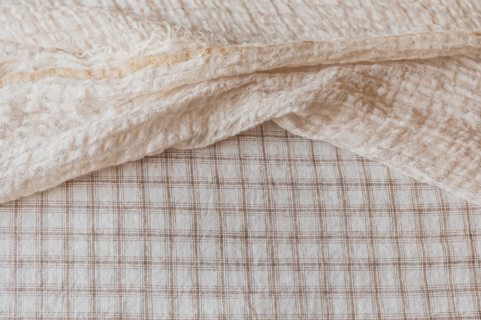 Primer plano de una manta de lino beige con textura cuadrillé.