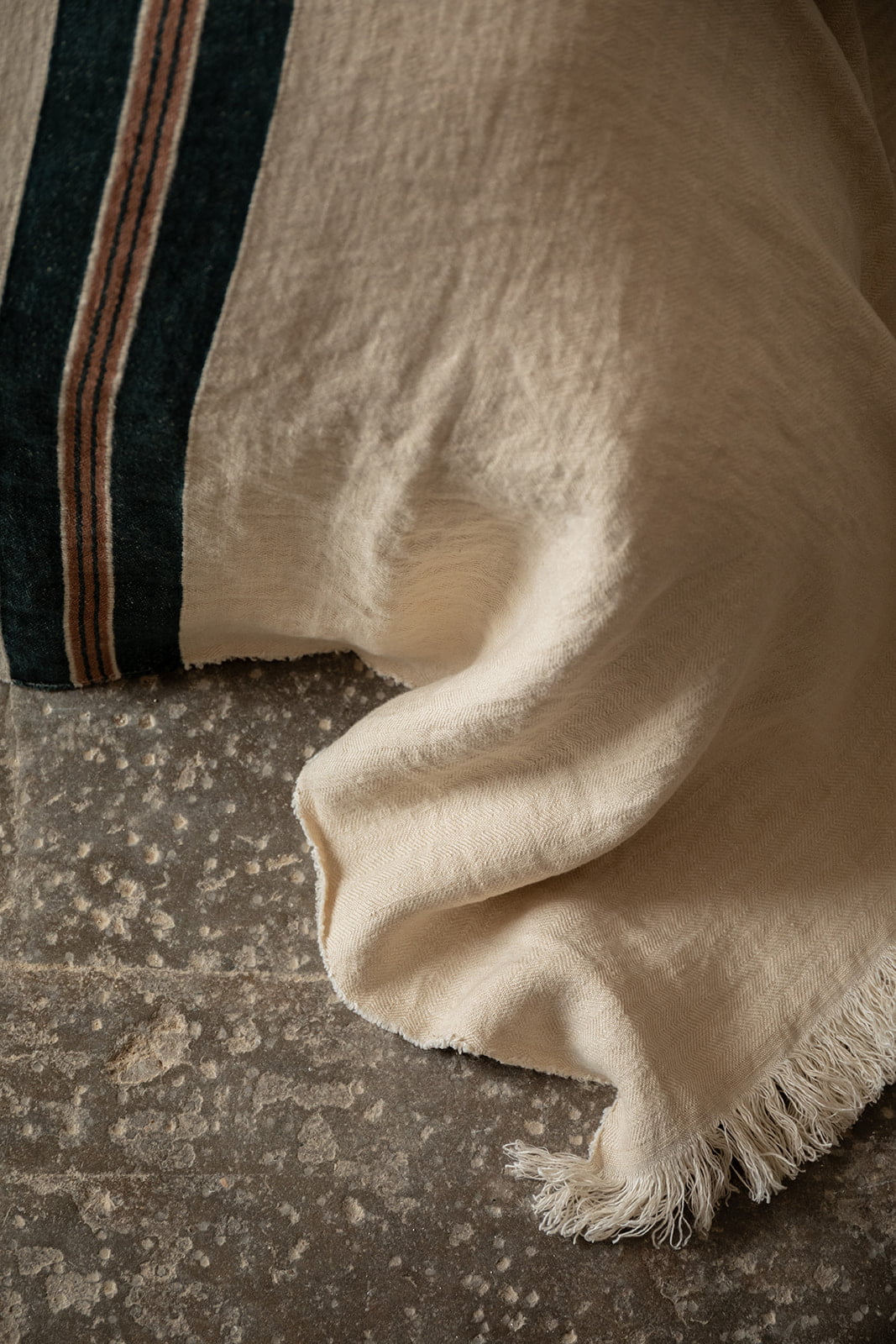 Detalle de manta a rayas en cama de estilo rústico.