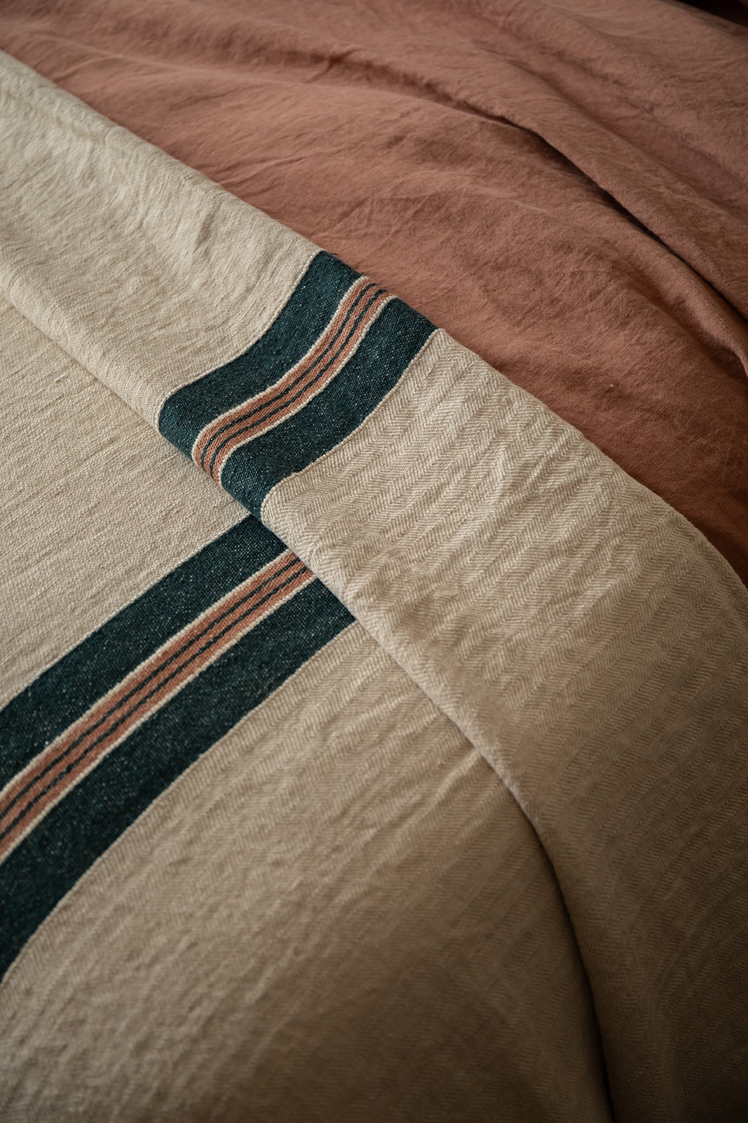 Detalle de manta a rayas en cama de estilo rústico.