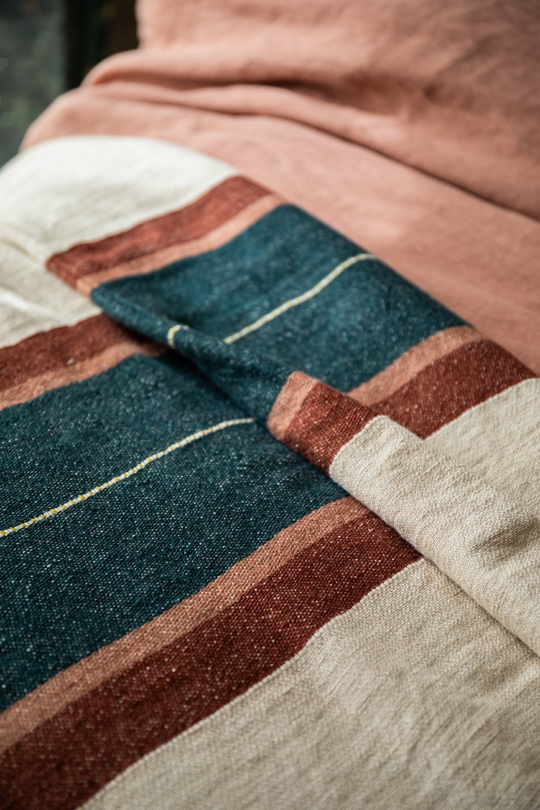 Detalle de manta a rayas en cama de estilo rústico.