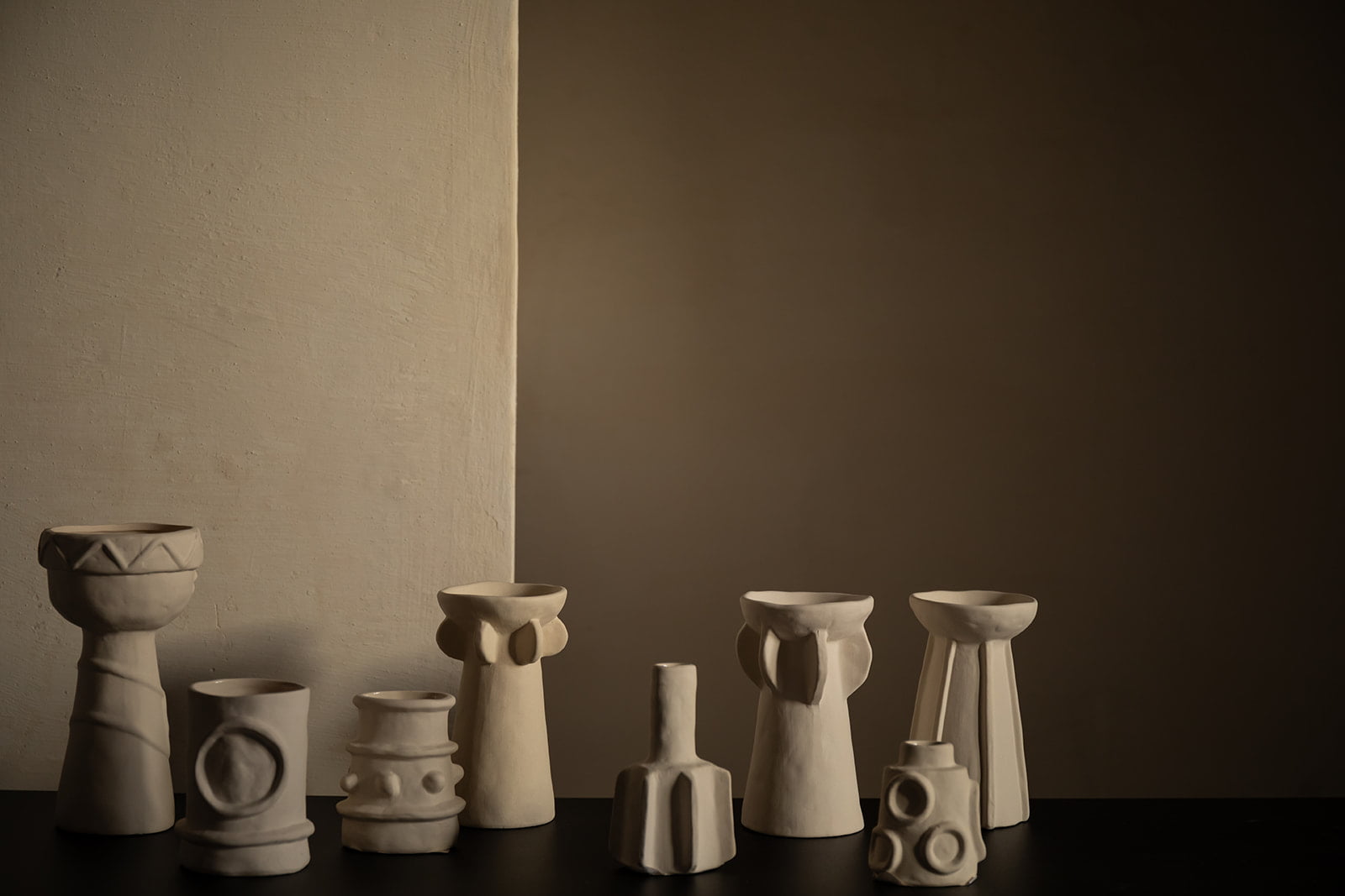 La Maison Barcelona 2024 Conjunto de jarrones de cerámica blanca sobre una mesa negra en una habitación con luz tenue