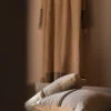 Cojines de lino apilados en tonos beige y gris en un ambiente cálido.