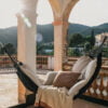 La Maison Barcelona 2024 Hamaca de tela beige con almohadas, vista desde una terraza con vistas a las montañas