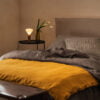 La Maison Barcelona 2024 Cama con ropa de cama gris y manta amarilla