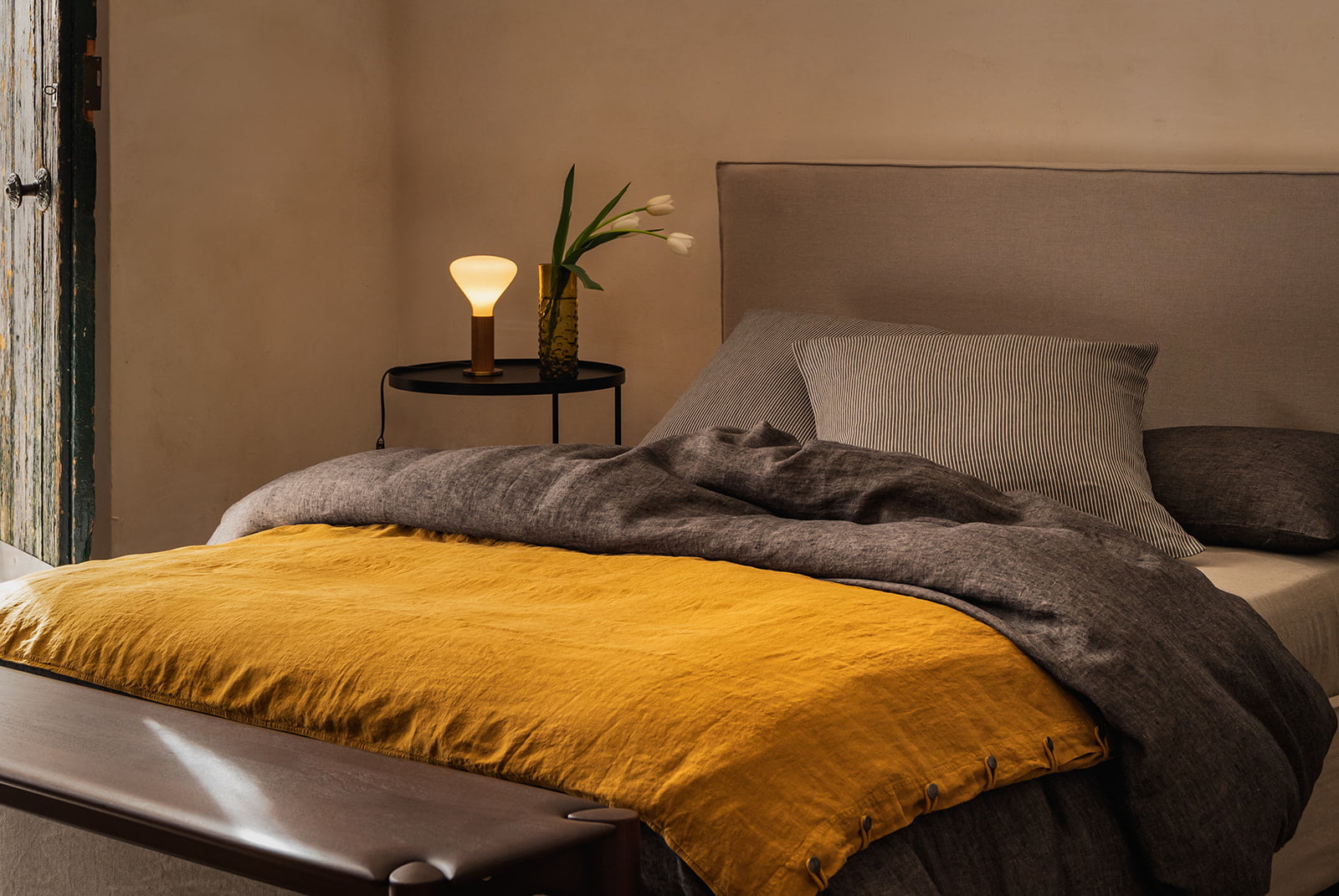 La Maison Barcelona 2024 Cama con ropa de cama gris y manta amarilla