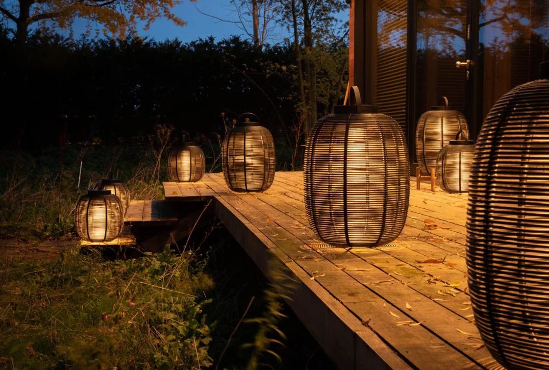 Lámpara de exterior encendida en un jardín por la noche.