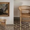 Silla de mimbre junto a un cuadro decorativo en una sala con piso de mosaico