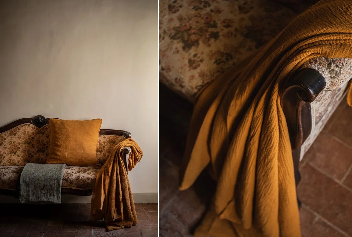 Cojines decorativos y manta de lana sobre sofá antiguo.